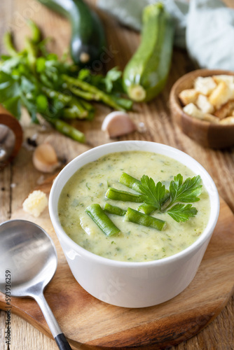 Vegan soup puree of green vegetables. Healthy diet low carb. Bowl of green bean and zucchini cream soup on a rustic table.