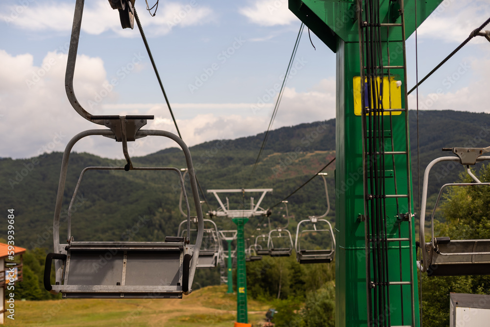 Mountain yellow lift on a summer day over the mountains. Old ski lift in the mountains in the sun. Carpathians, Ukraine. Mountain yellow lift on a summer day over the mountains. Old ski lift in the mountains in the sun. Carpathians, Ukraine.
