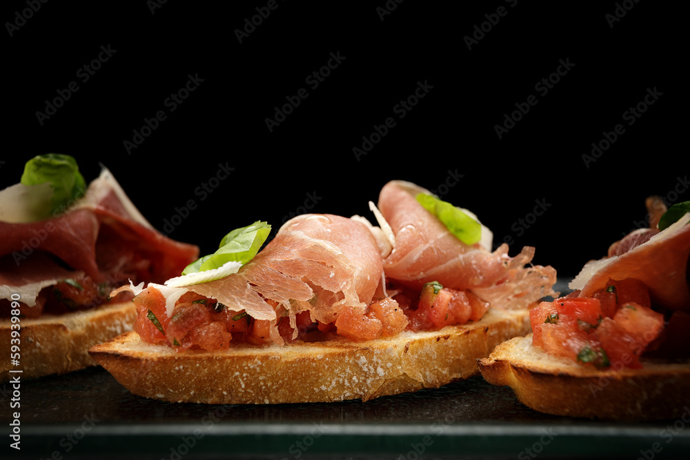 Savory Bruschetta with Salmon, Ham and Parmesan Cheese on Dark Background