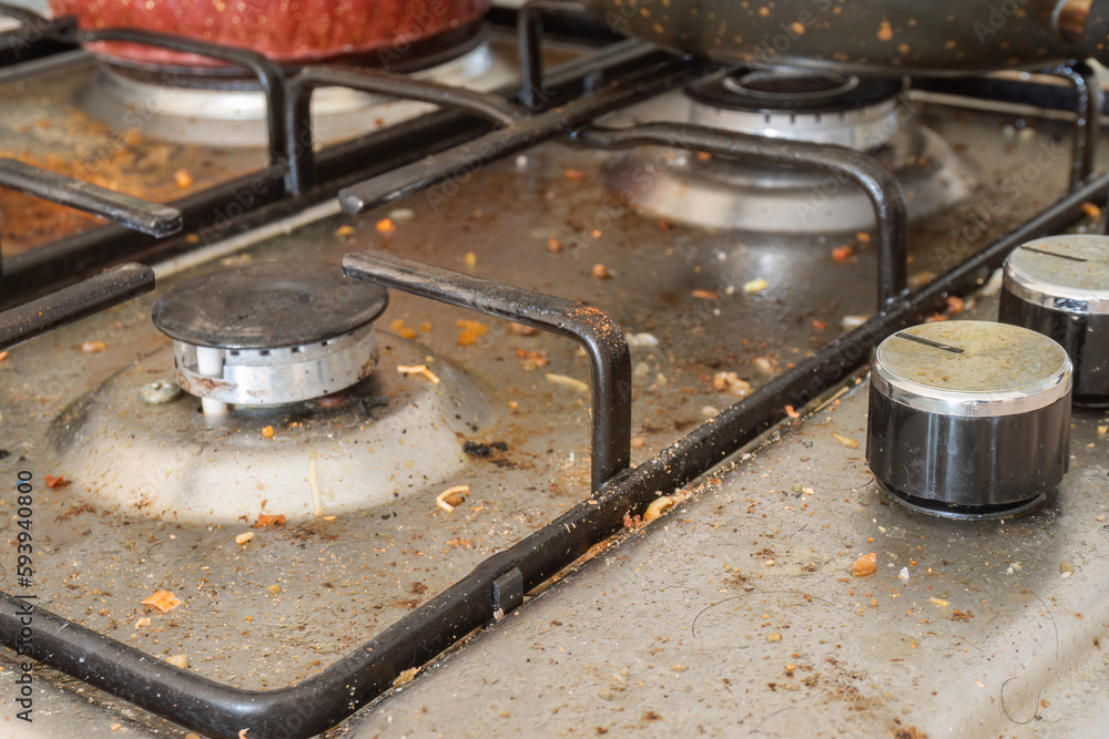 Dirty gas stove top with food leftovers. Selective focus. Unclean steel