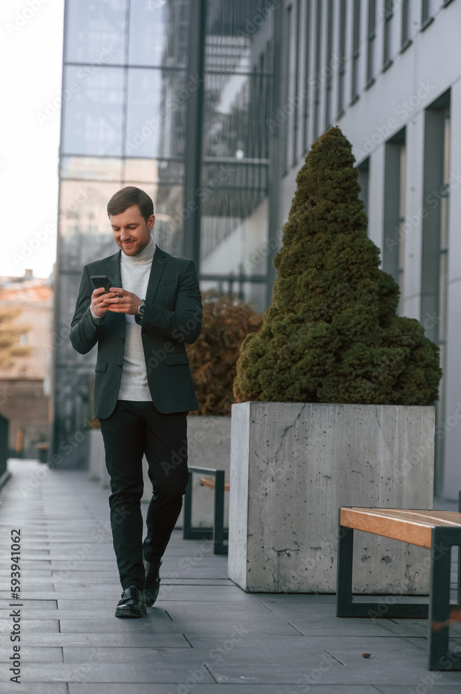 Windows behind the handsome man that is in the formal clothes using smartphone Windows behind the handsome man that is in the formal clothes using smartphone