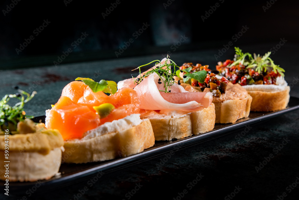 bruschetta set, various bruschettas with toppings on black plate bruschetta set, various bruschettas with toppings on black plate