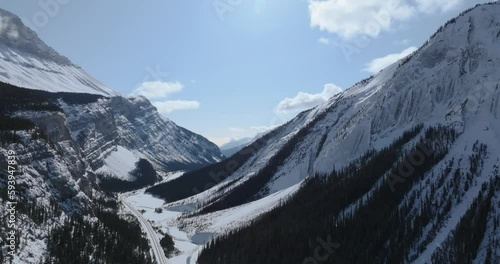 flying over highway between mountains in canadian rocky mountains touching the clouds