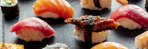 Sushi panorama. Nigiri with eel, tuna, salmon on a black background, Japanese food on a plate at an Asian restaurant
