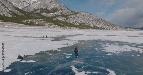 aerial view of man ice skating on frozen abraham lake in laberta, canada