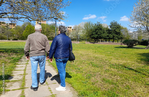Due anziani a passeggio nel parco urbano photo