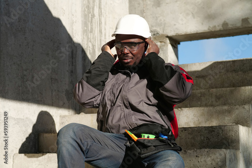 African american worker at project site has headache, he touches his head