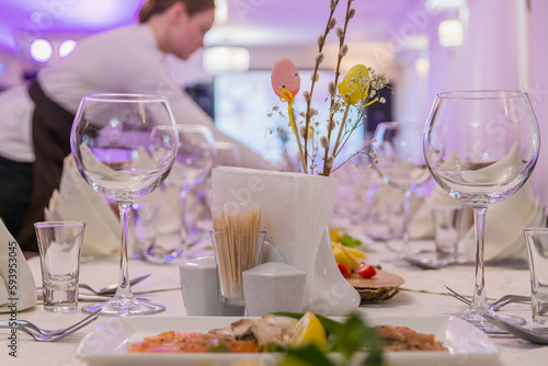Beautifully set banquet table for wedding or anniversary in restaurant, waiting for guests to arrive in lilac pink light.