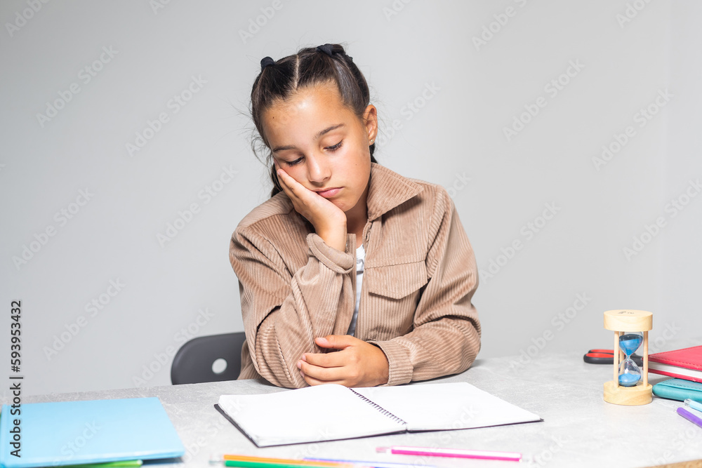 Pretty little girl tired of doing homework at table. Pretty little girl tired of doing homework at table.