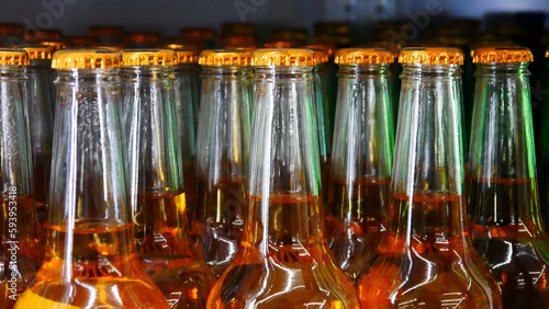 Many glass bottles of lager beer with golden caps in a store close-up