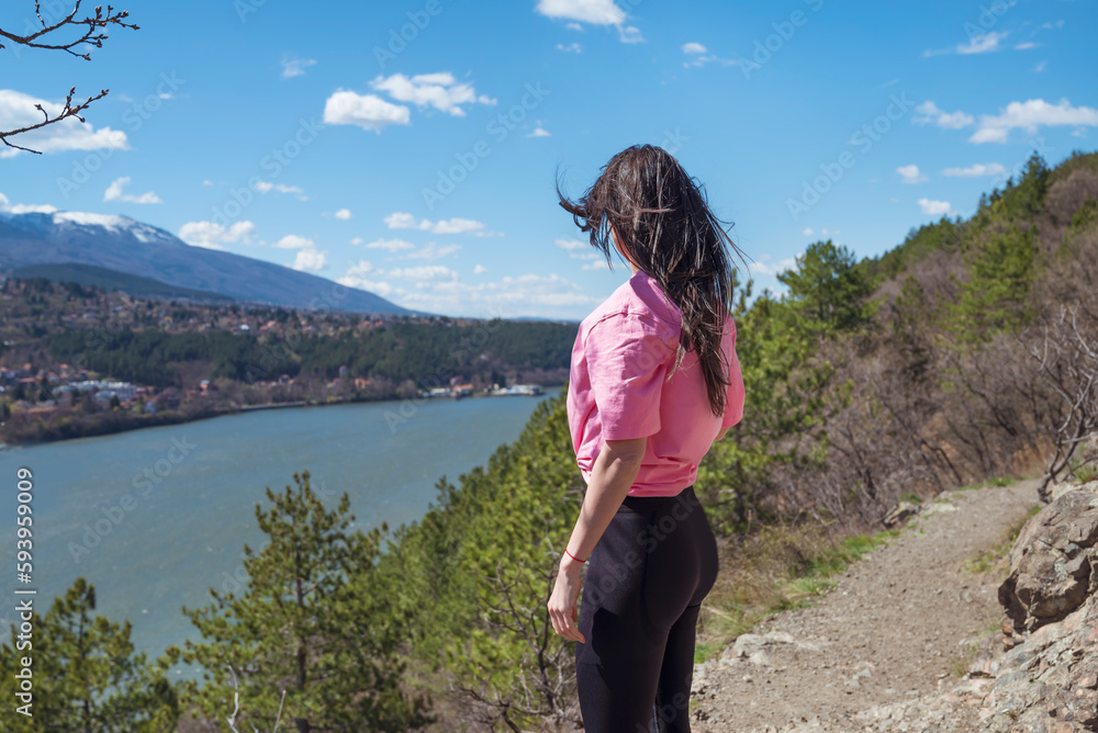 Traveler woman standing  high above a blue lake with stunning panoramic view .Traveling in the nature in Bulgaria 
