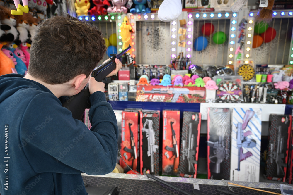 teenager with a rifle in a funfair teenager with a rifle in a funfair
