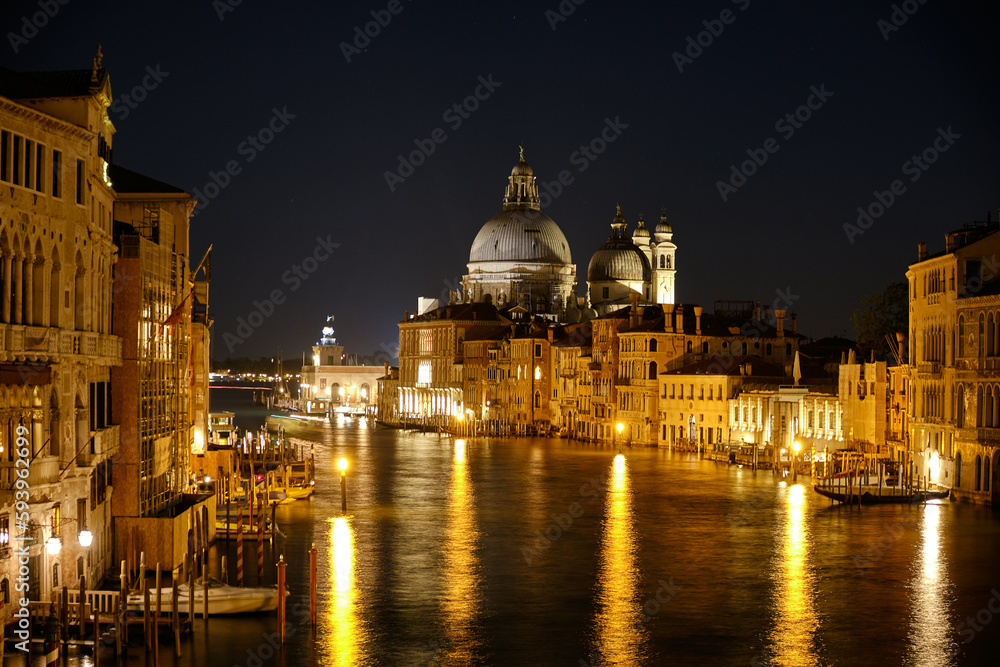 Venice, Italy: Night view of Venice Grand Canal with boats and Santa Maria della Salute church on sunset from Ponte dell'Accademia bridge. Venice, Italy