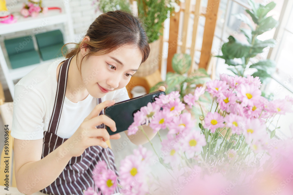 Pretty Asian Chinese woman florist taking photo of bouquet of flowers with smartphone in flower shop, Small business owner, entrepreneur, Using mobile phone Pretty Asian Chinese woman florist taking photo of bouquet of flowers with smartphone in flower shop, Small business owner, entrepreneur, Using mobile phone