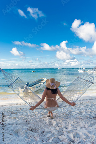Dominican Republic of Punta Cana, a girl in a hat on the ocean with turquoise water and palm trees.