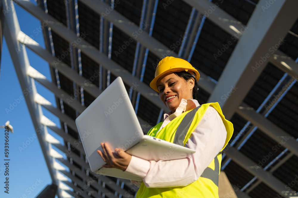 Black woman using laptop on construction site with solar batteries Black woman using laptop on construction site with solar batteries