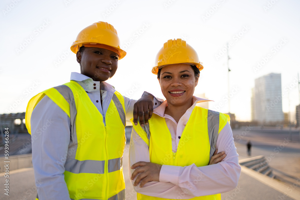 Happy ethnic female engineers on city street Happy ethnic female engineers on city street