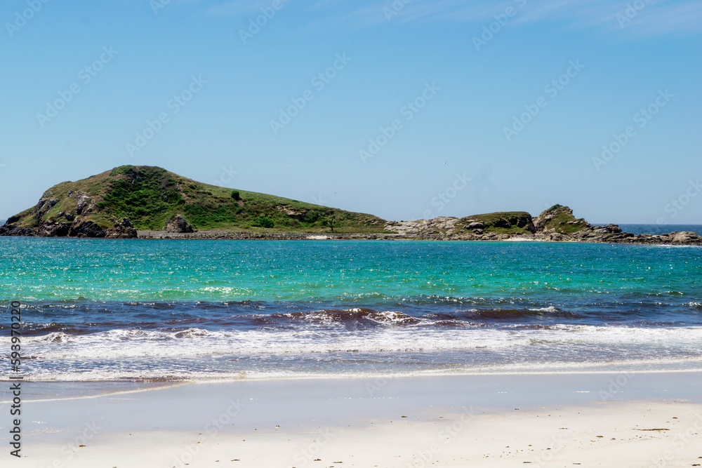 View of Praia dos Foguetes, close to the city of Cabo Frio, beach with sand full of brown marine vegetation, sea with clean waters in shades of green and blue and mountains in the background.