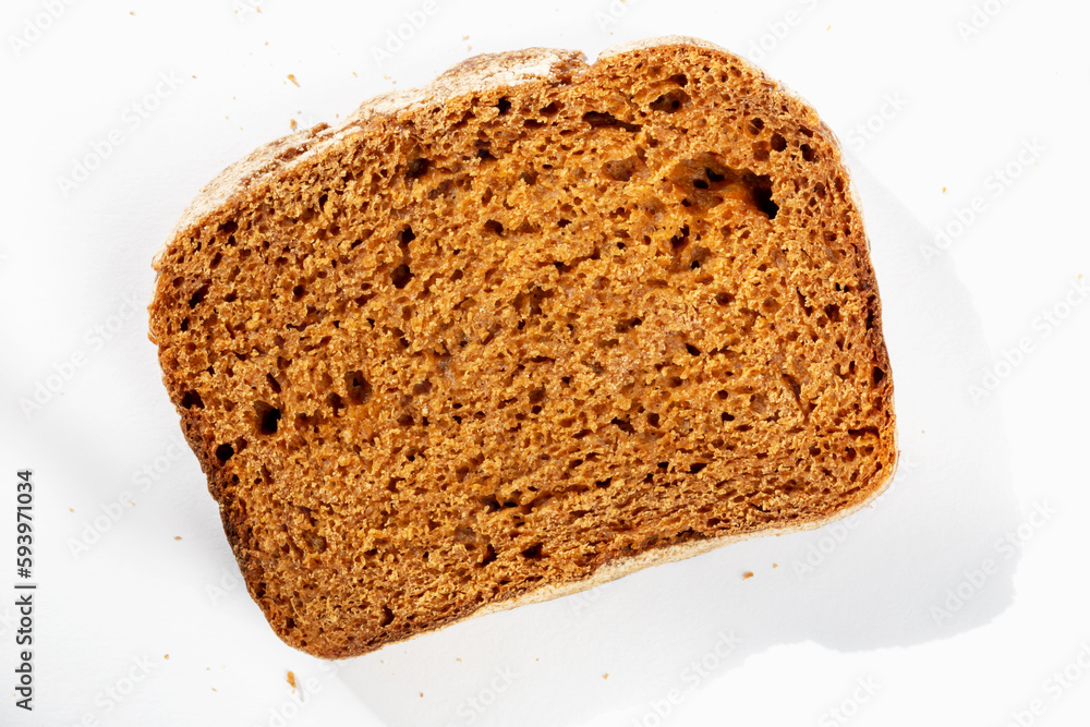 Slice of fresh delicious dark bread on white background in sunlight Slice of fresh delicious dark bread on white background in sunlight