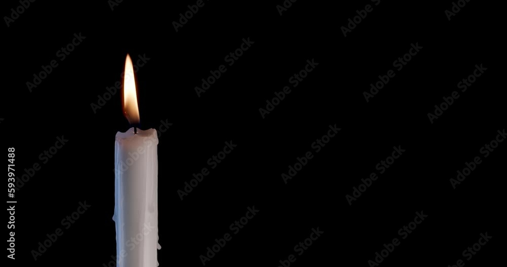 A single white candle burning. Isolated candle slow motion burning with dark background. White paraffin candle with yellow shades burns on a black background. Slow motion. A single white candle burning. Isolated candle slow motion burning with dark background. White paraffin candle with yellow shades burns on a black background. Slow motion.