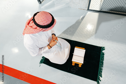 Photography Young arab muslim man reading the holy Quran in the office