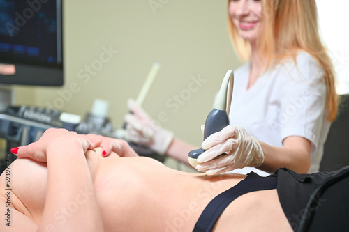 Professional female gynecologist performs an examination of the mammary glands using ultrasound scanner. Breast ultrasound examination. Prevention breast cancer. Screening after plastic surgery. photo