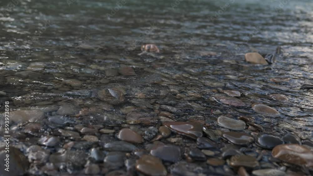 Riverbank with large stones and slow waves, creating a serene and calming natural scene. Riverbank with large stones and slow waves, creating a serene and calming natural scene.