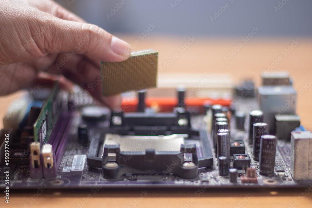 Technician preparing to assemble CPU into motherboard