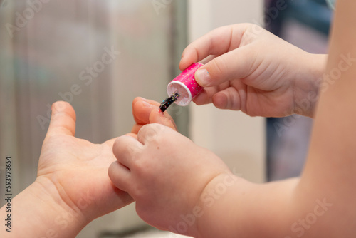 Little girls paint each other s nails with baby nail polish.