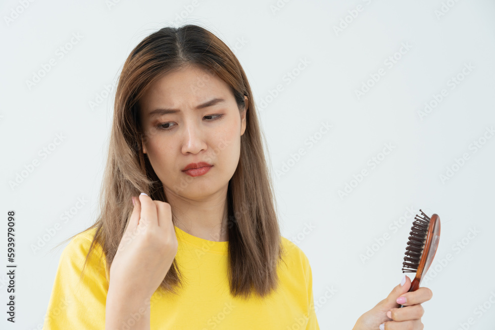 Asian woman very sad and upset looking at damaged hair, hair loss, hair thinning problem, vitamin deficiency, baldness, postpartum, biotin, zinc, menstrual or endocrine disorders, hormonal imbalance. Asian woman very sad and upset looking at damaged hair, hair loss, hair thinning problem, vitamin deficiency, baldness, postpartum, biotin, zinc, menstrual or endocrine disorders, hormonal imbalance.