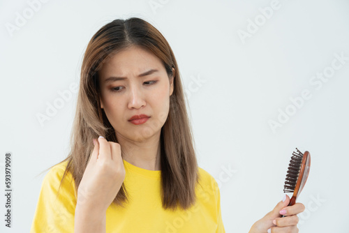 Asian woman very sad and upset looking at damaged hair, hair loss, hair thinning problem, vitamin deficiency, baldness, postpartum, biotin, zinc, menstrual or endocrine disorders, hormonal imbalance.