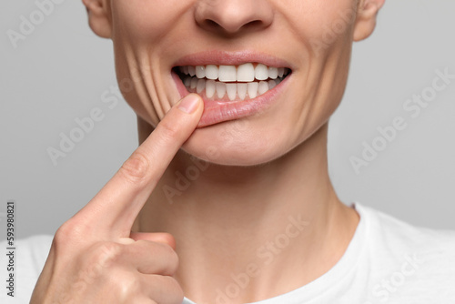 Woman showing healthy gums on light background, closeup