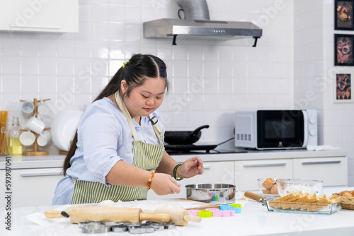 Asian person with Down syndrome cooking at kitchen photo