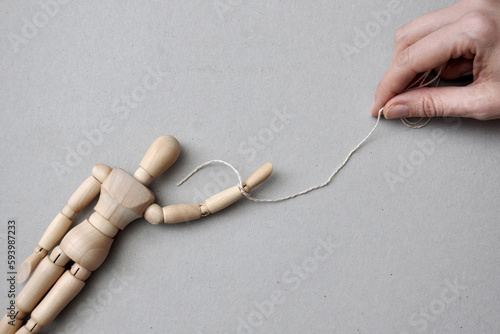 A wooden man with a rope on his arm. A symbol of dependence in relationships and manipulation. photo