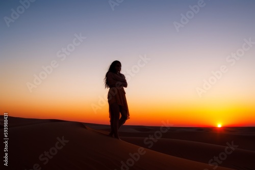 silhouette of person walking on the sand at sunset
