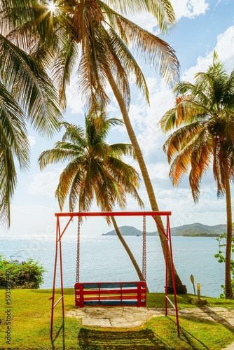 Vertical shot of a red swing by the sea on a sunny day in Cuba © Anselm Schwietzke/Wirestock Creators