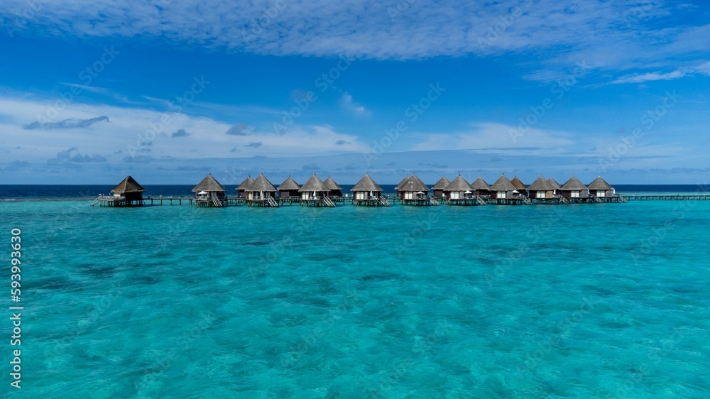 Scenic view of luxurious cabanas in the tranquil ocean against a blue sky in Maldives