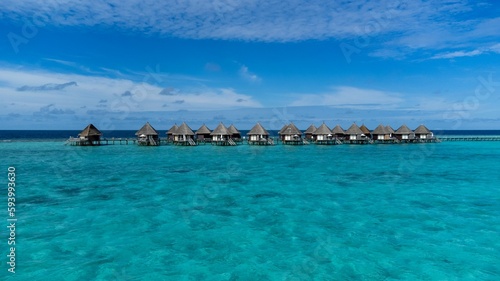 Scenic view of luxurious cabanas in the tranquil ocean against a blue sky in Maldives