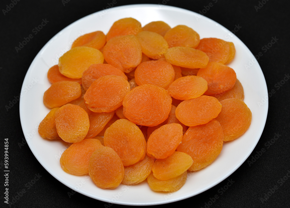 Dried fruits on a white plate. Dried apricot fruit halves without pits close-up. Dried fruits on a white plate. Dried apricot fruit halves without pits close-up.