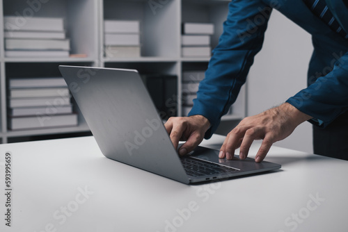 Close up view of businessman using laptop computer at office desk in the office room.