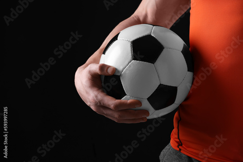 Athletic man with soccer ball on black background, closeup. Space for text