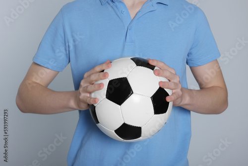 Boy with soccer ball on light grey background, closeup