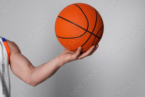 Athletic young man with basketball ball on light grey background, closeup. Space for text © New Africa