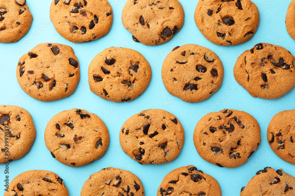 Many delicious chocolate chip cookies on light blue background, flat lay