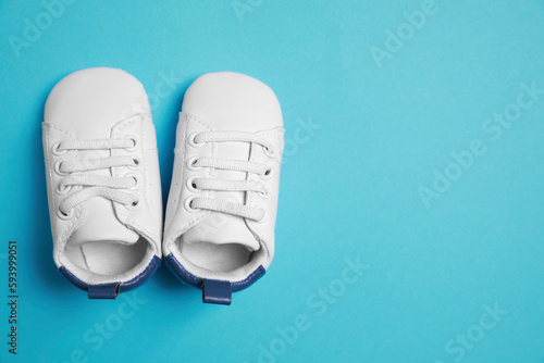 Cute baby shoes on light blue background, flat lay. Space for text