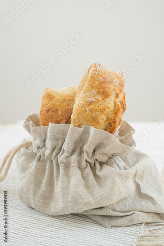 Delicious ciabatta resting in an eco-friendly bread bag, presented on a rustic table with a cozy tablecloth.