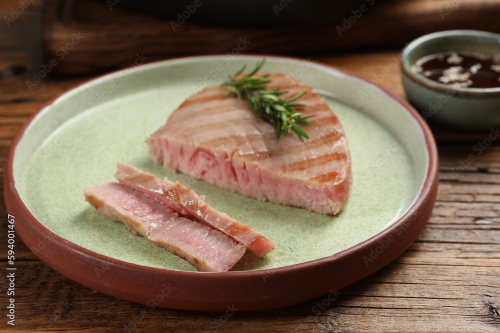 Delicious tuna steak with rosemary on wooden table, closeup Delicious tuna steak with rosemary on wooden table, closeup