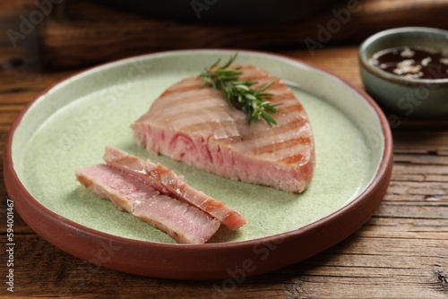 Delicious tuna steak with rosemary on wooden table, closeup