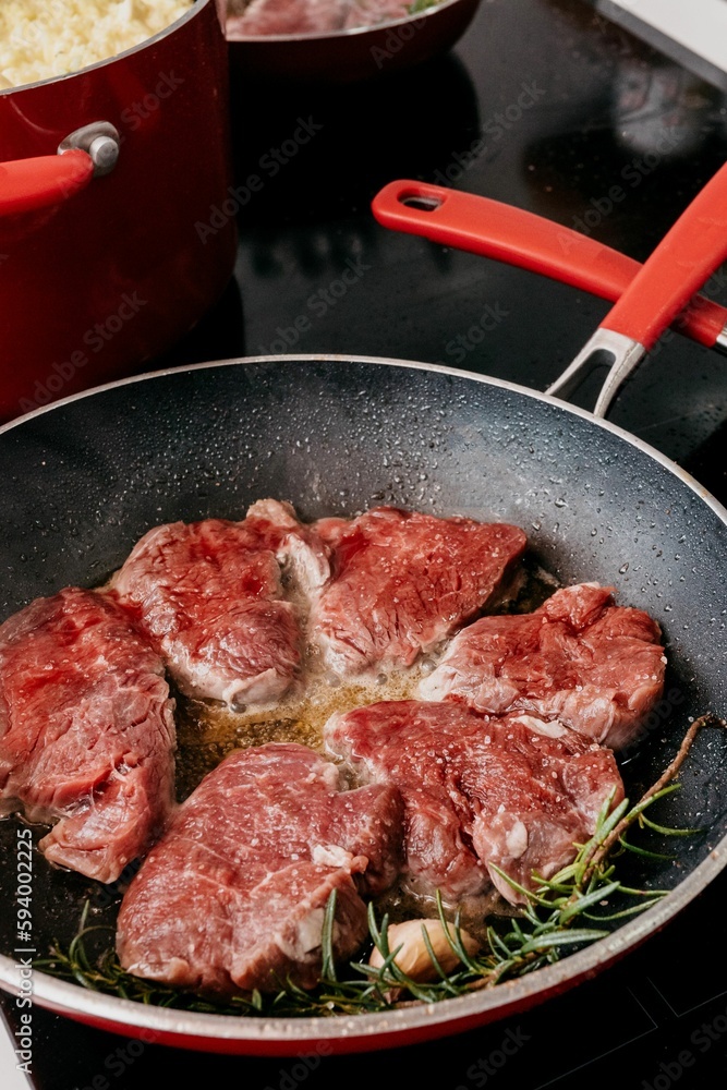 Close-up image of tender steak sizzling in a hot skillet on a kitchen stovetop Close-up image of tender steak sizzling in a hot skillet on a kitchen stovetop