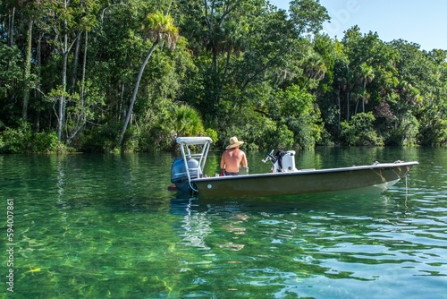 two people riding in a speed boat on the water by a forest